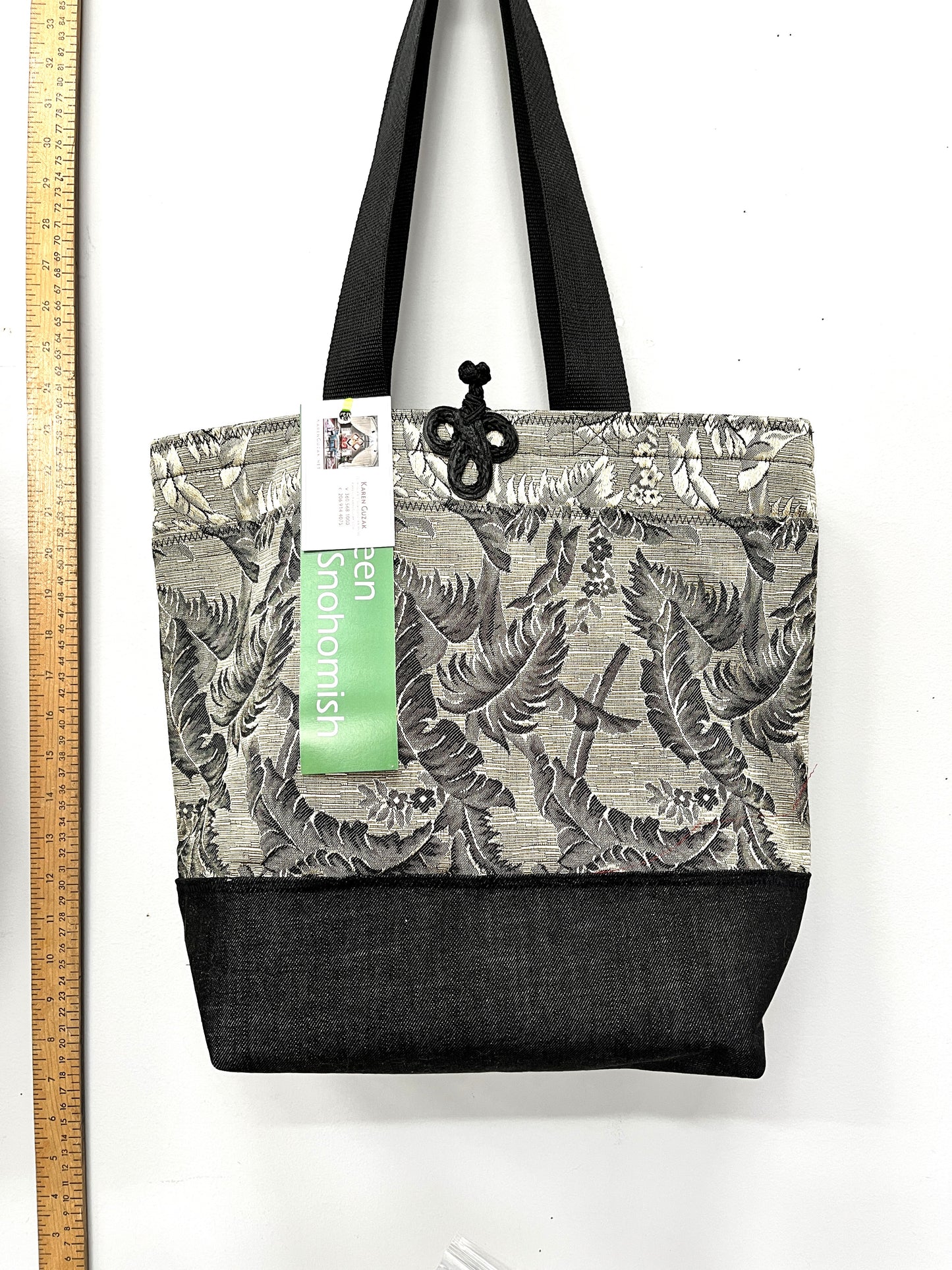 Tote bag with floral pattern and black base, next to a ruler for size reference.
